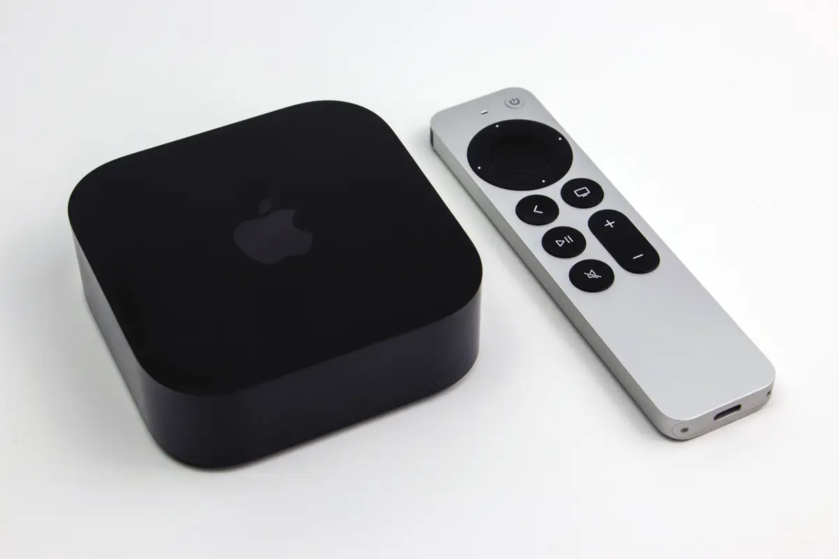 Apple TV 4K (3rd generation) set-top box beside its silver Siri Remote on a white surface